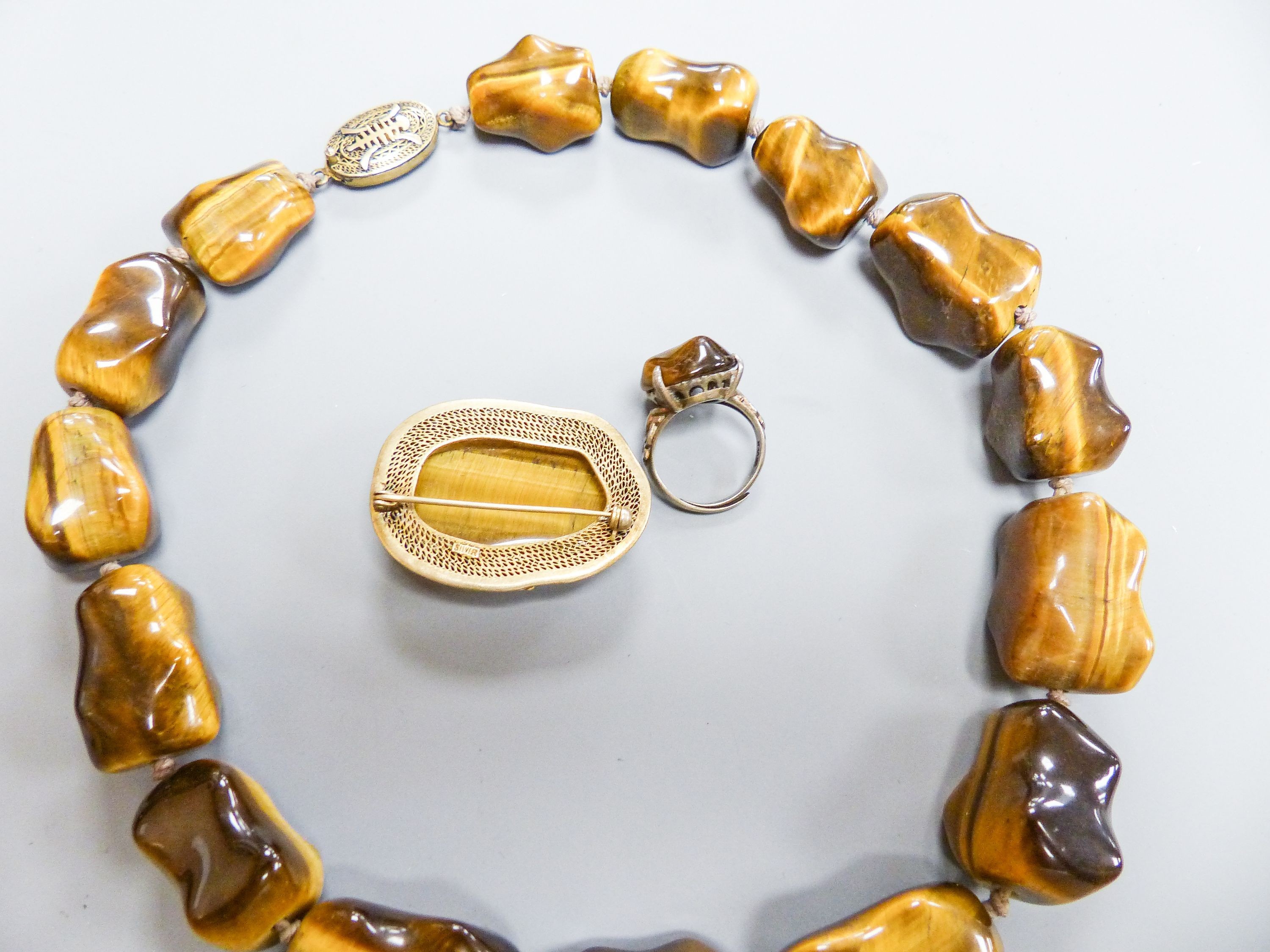 A Middle Eastern gilt white metal and tiger's eye pebble necklace, 48cm and a similar brooch and dress ring.